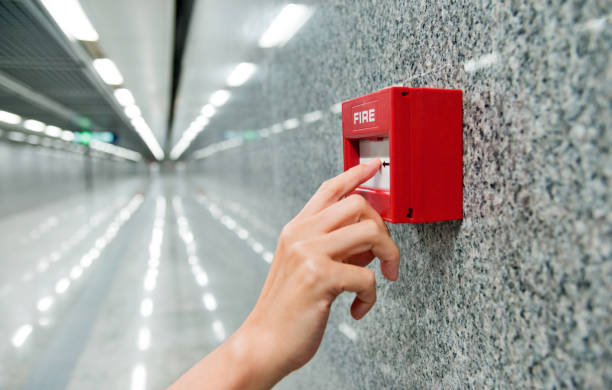 Human finger pushing fire alarm.